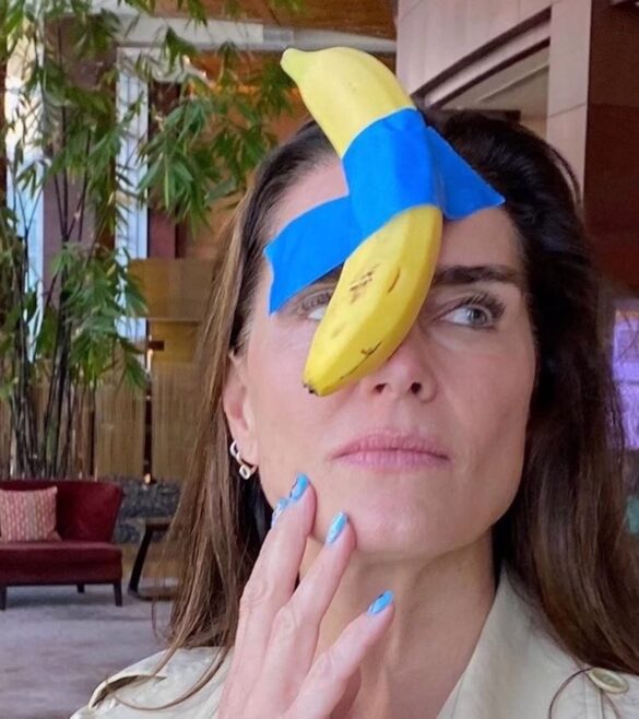 Brooke Shields posing humorously with Maurizio Cattelan’s The Comedian at Art Basel Miami Beach