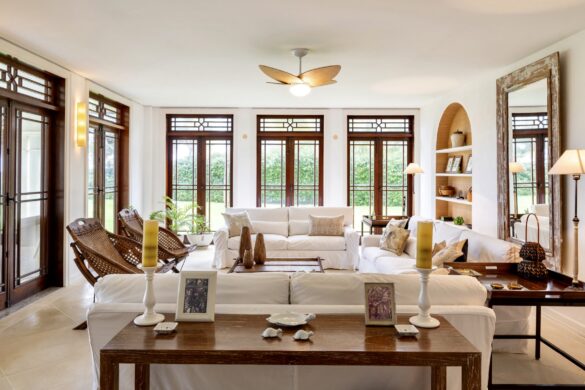 Elegant living room with white sofas, carved wood details, and Moorish arches framing views of palm trees and ocean"