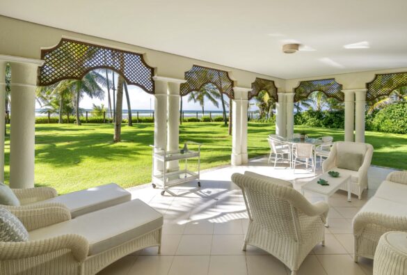 Collection of images showing the property's white colonial architecture, infinity pool, palm-lined gardens, elegant interiors with Moorish arches, and oceanfront views from various angle