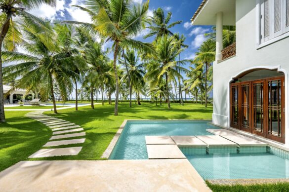 Collection of images showing the property's white colonial architecture, infinity pool, palm-lined gardens, elegant interiors with Moorish arches, and oceanfront views from various angle