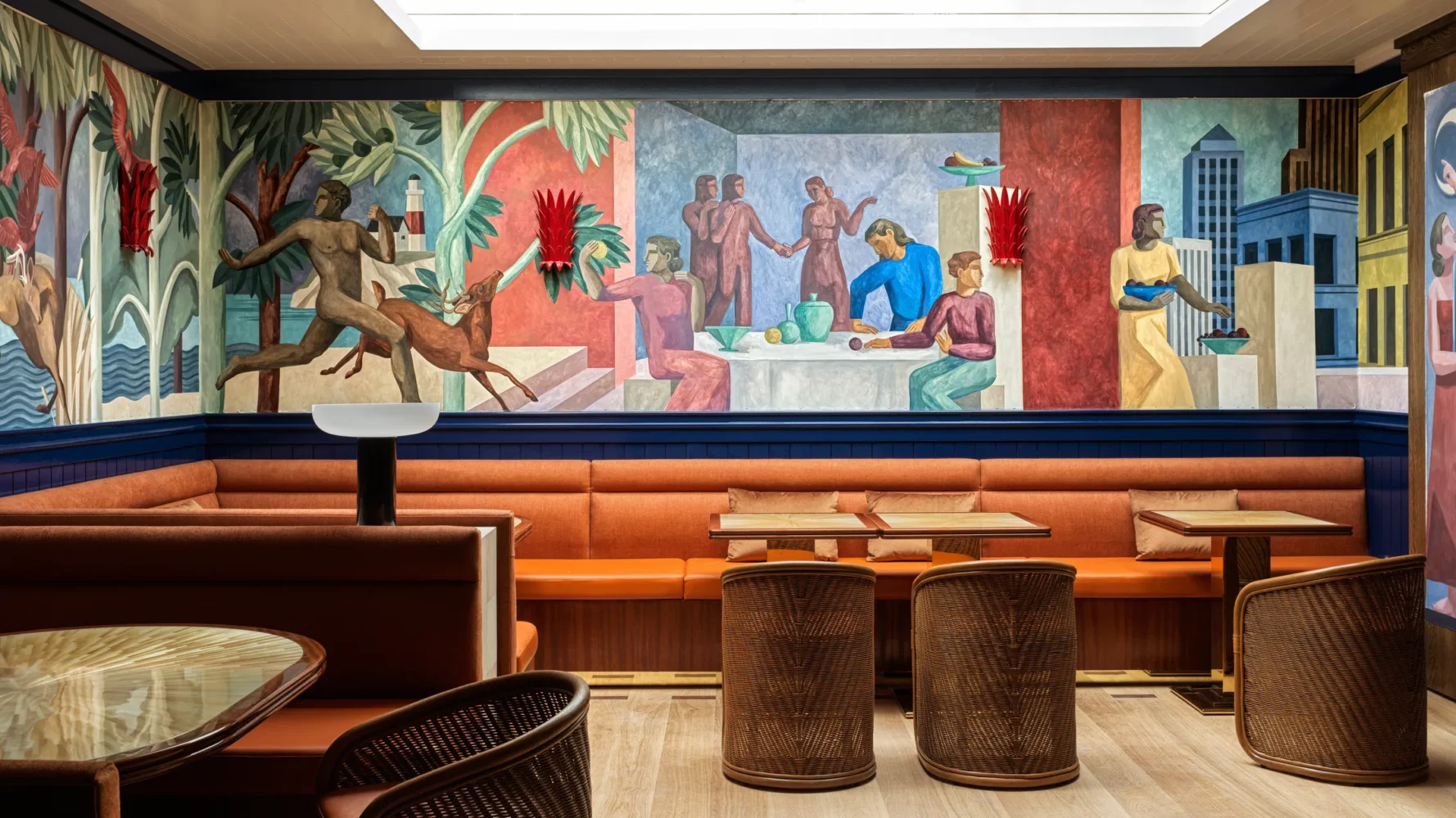 Restaurant banquette seating beneath Art Deco-style mural depicting figures in an urban landscape with tropical elements