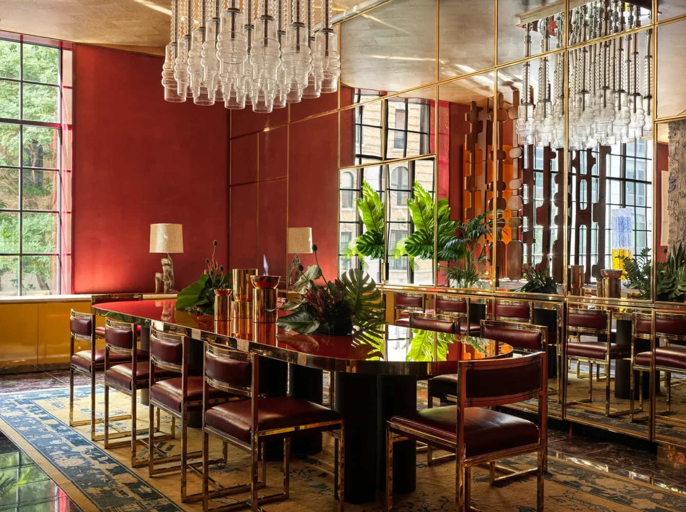 Luxury restaurant interior with red lacquered walls, crystal chandelier, brass mirrors, and burgundy leather dining chairs around a reflective table